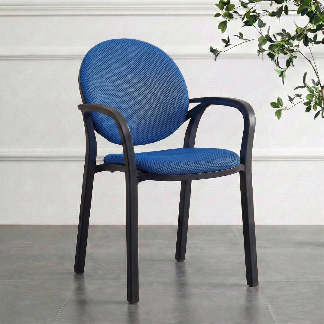 Blue cushion with smoke gray frame on a gray floor against a white wall with a plant.