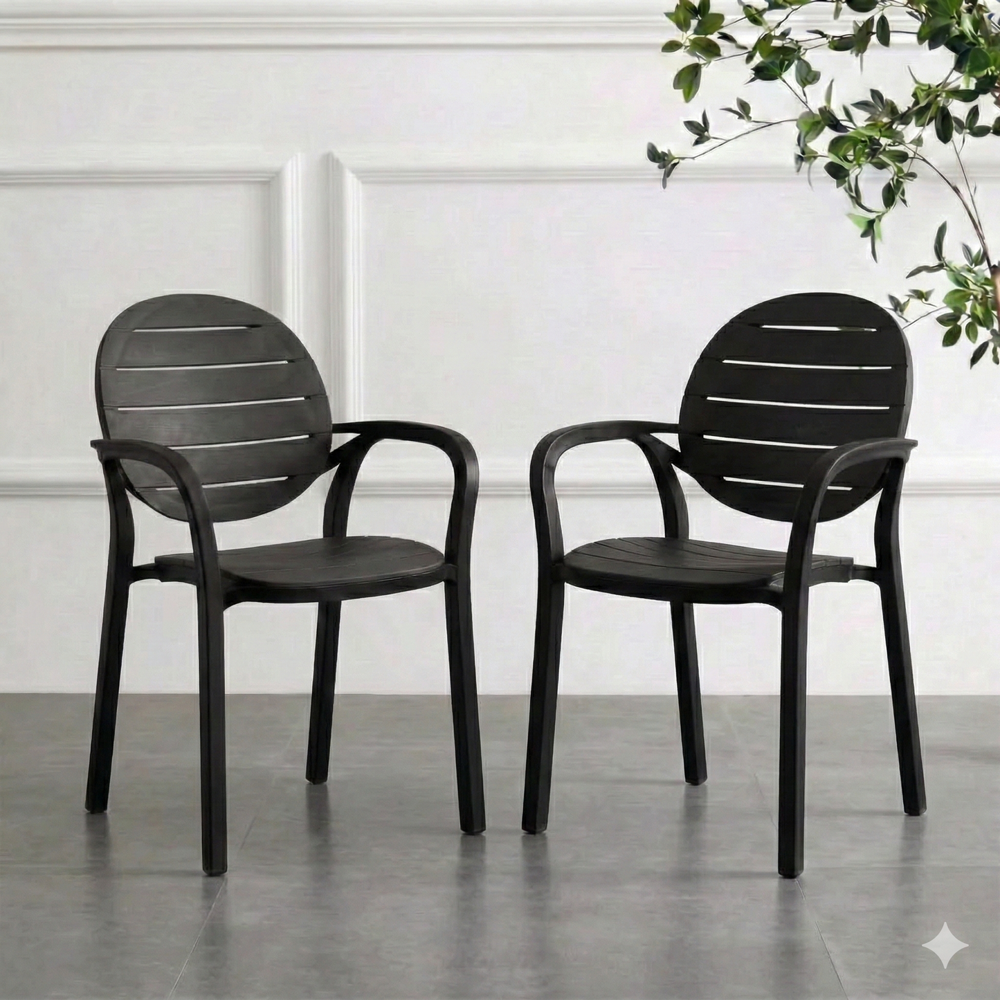 Two smoke gray chairs on a gray floor with a white wall and plant in the background
